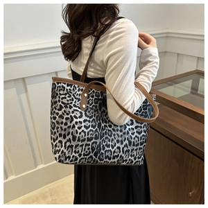 Detail of leopard print tote bag with brown leather handles and gold rivet accents