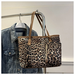 Close-up of leopard print tote bag with matching zippered pouch on a metal hanger