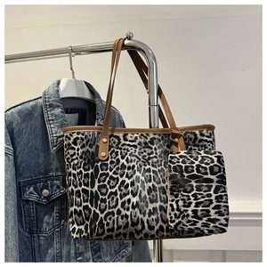 Detail of leopard print tote bag set featuring brown leather trim and golden hardware