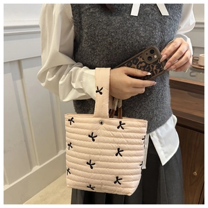 Dettaglio di borsa in cotone trapuntato rosa con ricami di farfalle nere e trama soffice