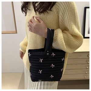 Dettaglio borsa shopper trapuntata nera con ricami a fiocco rosa e chiusura a scatto