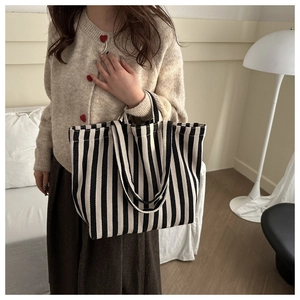 Classic black and white striped canvas tote bag styled with a beige knit sweater