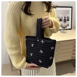 Dettaglio della borsa trapuntata nera con fiocchi ricamati rosa e chiusura magnetica