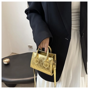 Detail of a mini gold crossbody bag with diamond quilting and metallic finish on a model