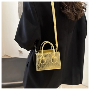 Detail view of a gold metallic quilted crossbody bag worn over a black blazer