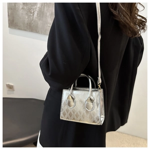Detail of silver metallic crossbody bag with diamond quilted pattern and thin shoulder strap