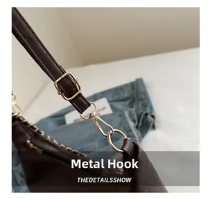 Détail du crochet en métal doré et boucle réglable sur un sac cabas marron foncé
