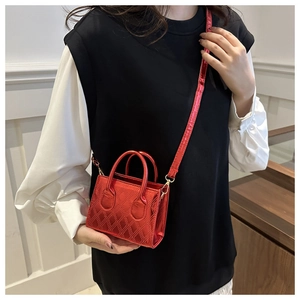 Detail of metallic red quilted mini crossbody bag with dual handles and slim shoulder strap