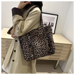 Close-up of leopard print canvas tote bag styled with a beige trench coat for workwear