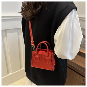 Close-up of metallic red quilted crossbody bag with dual handles and thin shoulder strap