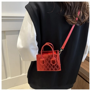 Close-up of a mini red quilted leather crossbody bag with metallic finish and top handles