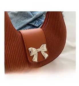 Close-up of brown textured hobo bag with a silver metallic bow and zipper detail