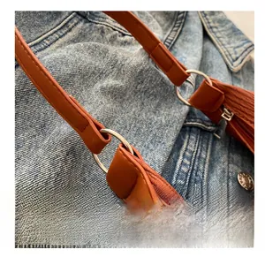 Close-up of caramel orange ruched bag texture with silver metal ring buckle and stitching