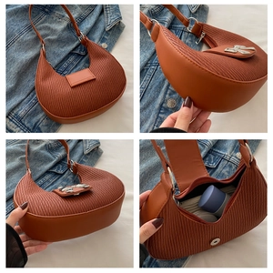 Macro view of terracotta crescent bag showing ruched texture and silver bow detail