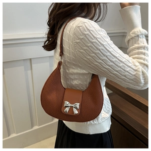 Detail of brown crescent bag with pleated texture and silver bow metal buckle
