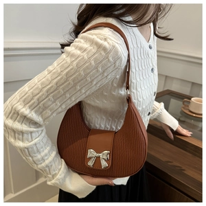 Detailed view of brown textured leather crescent bag with silver metal bow clasp