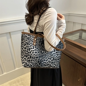 Vintage leopard print tote bag with brown leather trim shown on shoulder in daily use