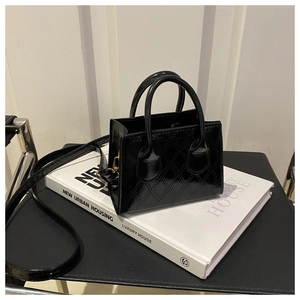 Detail of glossy patent leather mini bag with quilted rhombus pattern and metal hardware