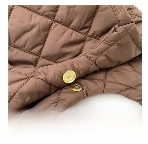 Détail de boucles magnétiques dorées et texture matelassée sur un sac cabas marron