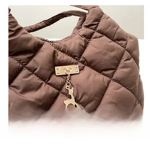 Gros plan d'un sac cabas marron matelassé avec texture bouffante et pendentif cerf doré