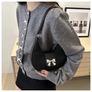 Detail of black crescent hobo bag featuring pleated texture and silver bow accent