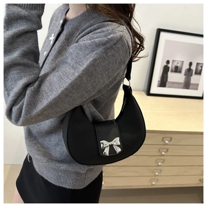 Detail of black crescent hobo bag with pleated texture and silver metal bow decoration