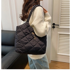 Détail d'un sac cabas matelassé avec surpiqûres losanges et breloque cerf doré