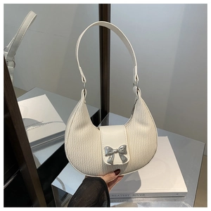 Close-up of white crescent handbag with pleated texture and silver bow buckle detailing
