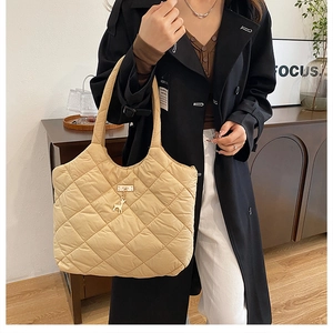 Détail du sac cabas matelassé beige avec pendentif cerf doré et motif en losange