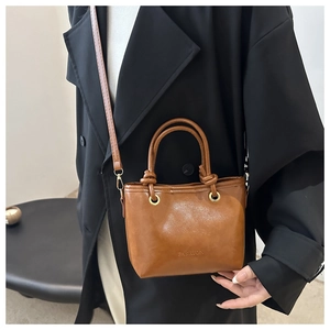 Detail of vintage brown leather bucket bag with FASHION embossing and shoulder strap