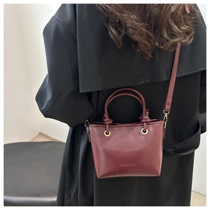 Gros plan du sac seau bordeaux vintage avec poignée nouée et logo de mode embossé