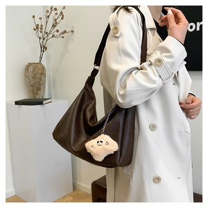 Détail du sac croissant en cuir marron foncé avec un pendentif étoile en peluche douce