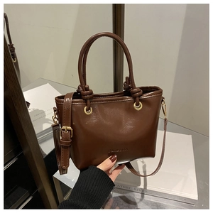 Gros plan d'un sac à main marron brillant avec poignée nouée et logo Fashion