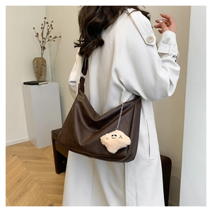 Détail d'un grand sac cabas en cuir marron foncé avec charme étoile en peluche et texture
