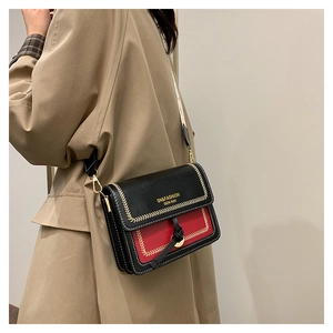 Close-up of black and red crossbody bag featuring gold woven stitching and metal hardware