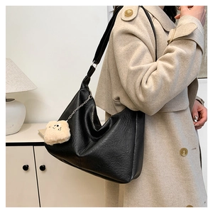 Detail of black pebbled faux leather hobo bag with a cute plush bear charm accessory