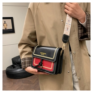 Detail of a retro color-block handbag with embroidered strap and gold V-stitch accents