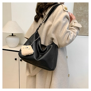 Detail of black hobo bag with leather texture and cute plush toast doll pendant charm