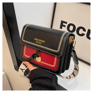Detailed shot of black and red crossbody bag with golden V-stitching and lettered strap