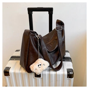Détail d'un grand sac cabas en cuir marron avec charm nuage sur une valise