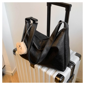 Détail du grand sac cabas en cuir souple noir avec charm ours sur valise blanche
