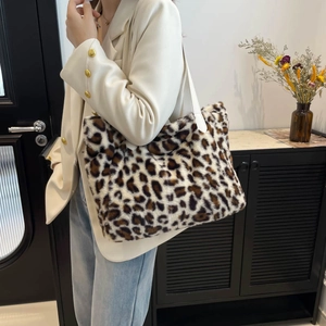 Sac cabas tendance en peluche léopard avec large bandoulière porté à l'épaule