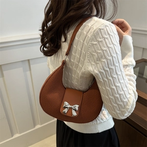 Brown crescent bag with pleated texture and silver bow detail worn over the shoulder