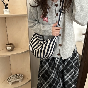 Sac hobo en toile rayé bleu et blanc avec large bandoulière porté par un mannequin