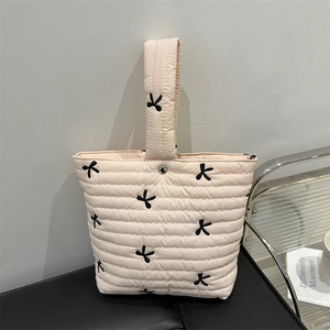Elegante borsa a secchiello trapuntata beige con ricamo a fiocco nero e manico superiore