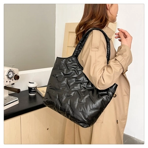 Dettaglio di una grande borsa tote trapuntata nera con cuciture a V su nylon lucido