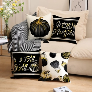 Set of 4 fall pumpkin pillow covers in black and gold on a cozy beige sofa