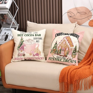 Pink and beige Christmas linen pillow covers with holiday illustrations on a cozy sofa