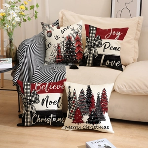 Lot de quatre housses de coussin de Noël avec motifs sapin et nœuds sur un canapé
