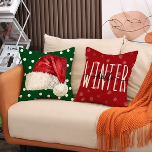 Red and green Christmas pillow covers with winter tree patterns on a beige sofa